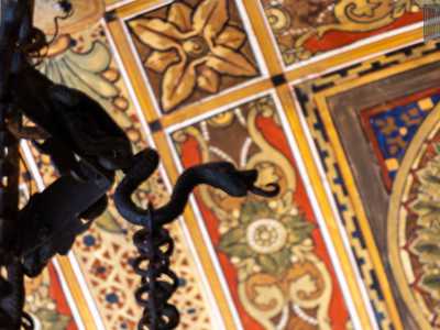 Dal centro pende un lampadario in ferro nero con piccoli serpenti, emblema massonico della salvezza